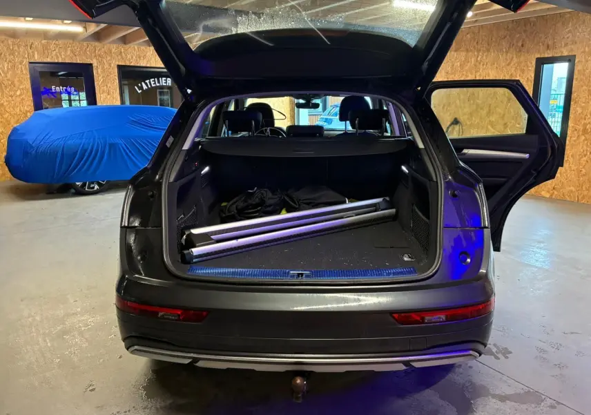 Vue arrière d'un Audi Q5 gris 2024 avec coffre ouvert et porte arrière droite ouverte, montrant un crochet d'attelage.