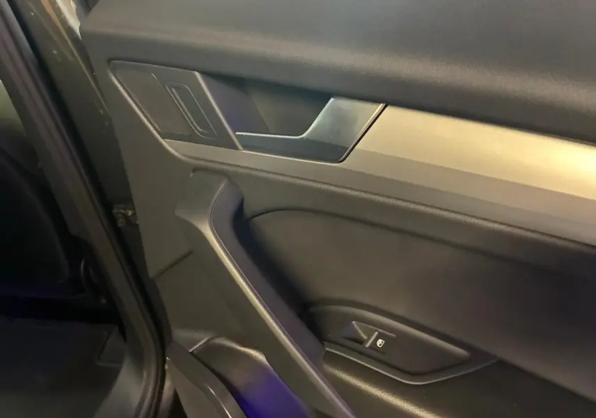 Gros plan sur la porte intérieure côté gauche de l'Audi Q5 gris, avec poignée et commande de vitre intégrée.