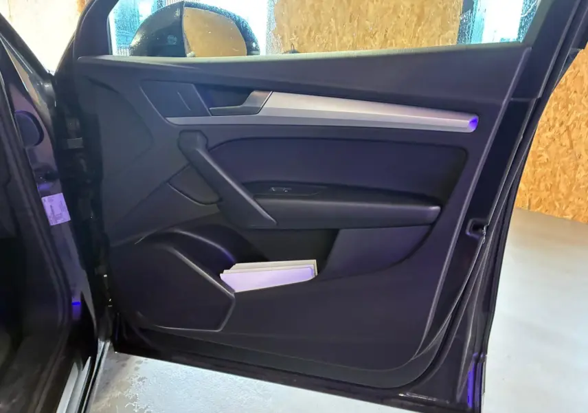 Vue intérieure de la porte avant gauche gris foncé de l'Audi Q5 2024 avec insert argenté et rangement inférieur.