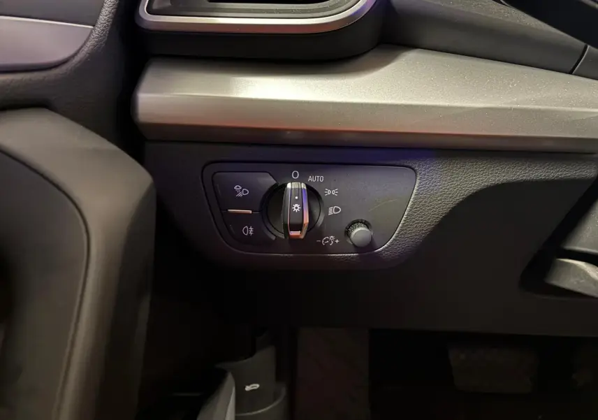 Gros plan sur le panneau de commande des phares à gauche du tableau de bord d’un Audi Q5 gris 2024.
