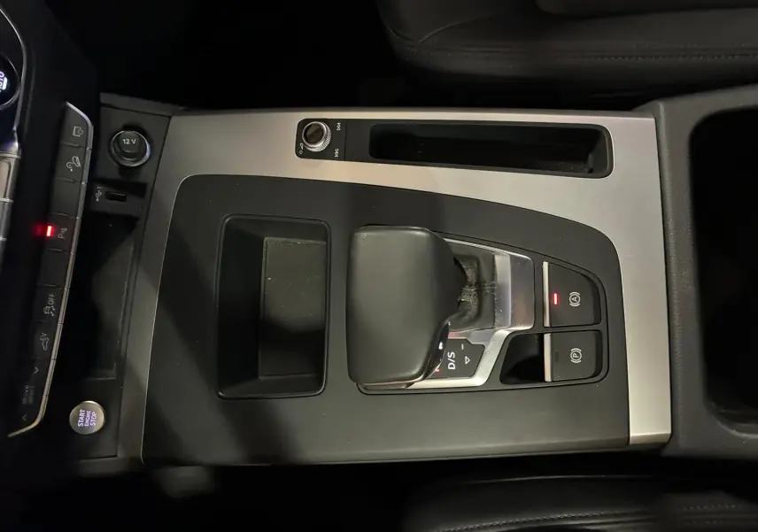 Vue rapprochée de la console centrale grise et noire de l’Audi Q5 2024 avec levier de vitesse S tronic et bouton Start/Stop.