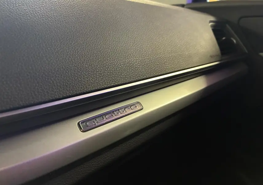 Détail intérieur du tableau de bord avec insert aluminium et logo quattro sur Audi Q5 gris 2024.