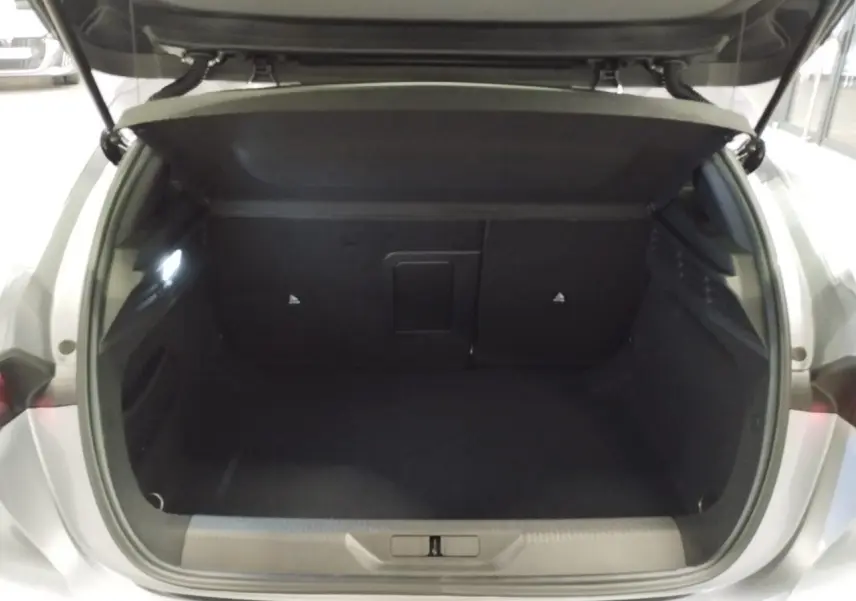 Coffre ouvert vu de l'arrière d'une Peugeot 308 gris Artense, montrant l'espace de chargement vide et l'éclairage intérieur.