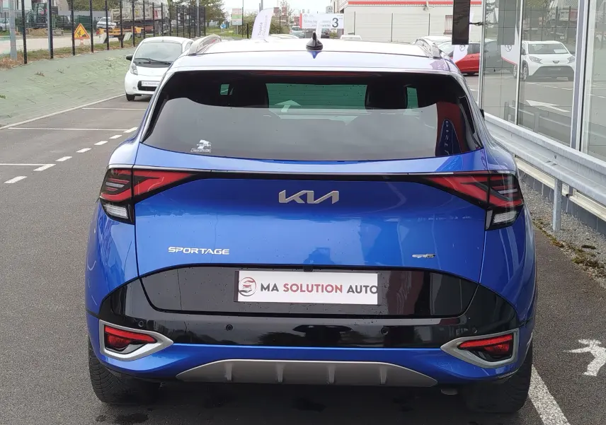 Vue arrière d'un Kia Sportage bleu fusion métallisé 2022 avec feux arrière étirés et logo Kia moderne.