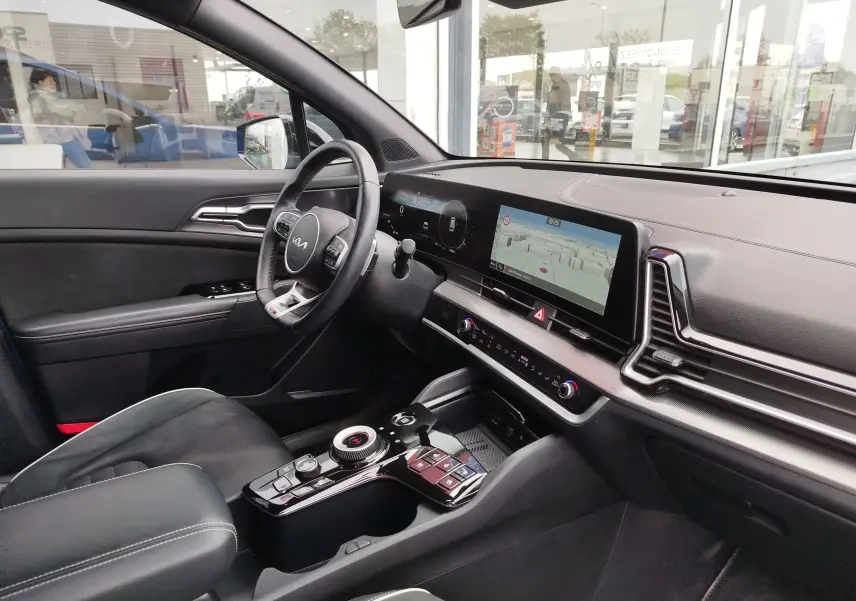 Vue intérieure côté conducteur du Kia Sportage 2022, tableau de bord numérique et console centrale moderne en noir.