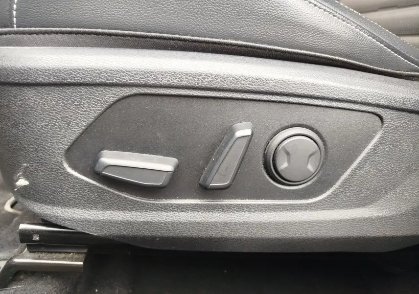 Détail des commandes de réglage électrique du siège conducteur en cuir noir dans un Kia Sportage 2022.