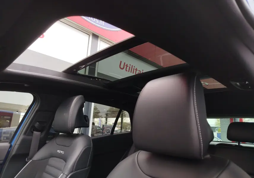 Vue intérieure du Kia Sportage bleu Fusion 2022, mettant en valeur les sièges en cuir noir GT-Line et le toit ouvrant panoramique.