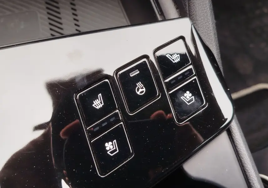 Détail des commandes de sièges chauffants et ventilés sur la console noire brillante du Kia Sportage 2022.