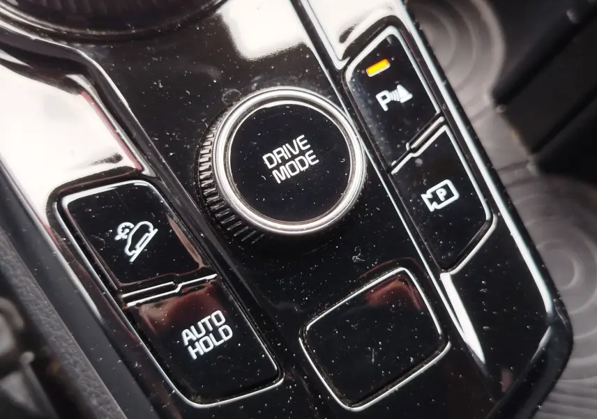 Gros plan sur la molette Drive Mode et les boutons de contrôle du frein à main et assistance stationnement dans le KIA Sportage 2022.