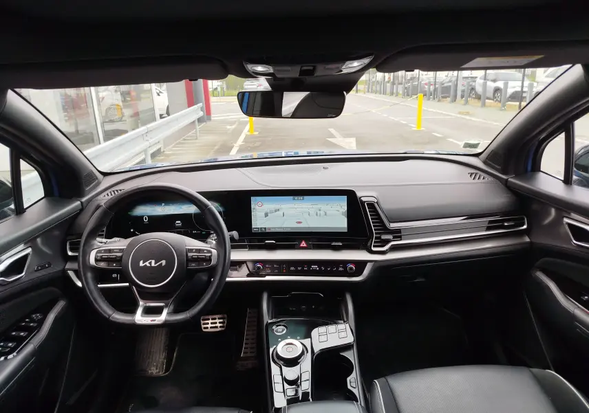 Vue intérieure avant du Kia Sportage 2022 bleu métallisé, avec tableau de bord numérique et écran tactile central large.