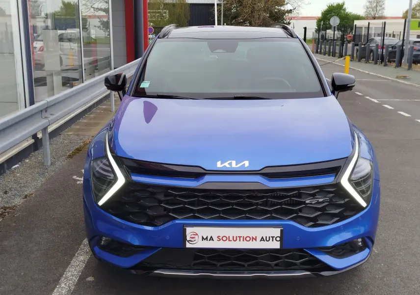 Vue avant d'un Kia Sportage bleu métallisé avec phares LED en forme de V et calandre noire hexagonale.