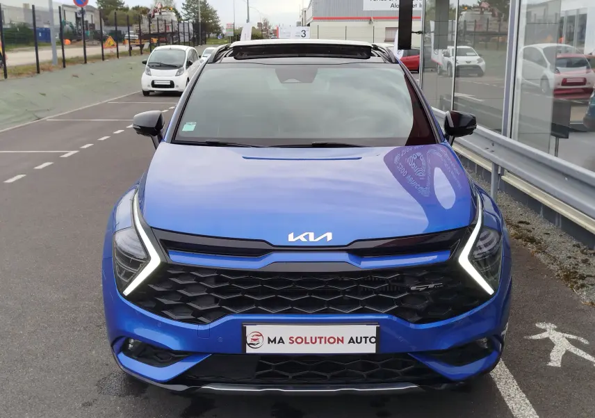 Vue avant d’un KIA SPORTAGE bleu fusion métallisé avec calandre noire et feux LED en forme de V lumineux.