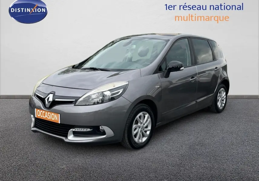 Renault Scénic III gris en 3/4 avant droit, avec calandre chromée et feux avant profilés visibles.