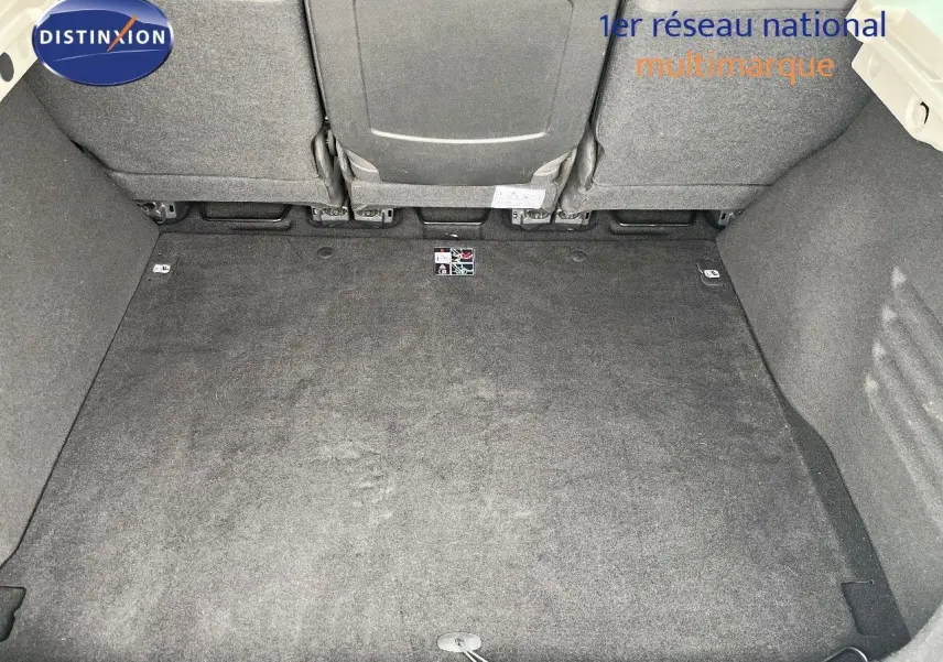 Coffre spacieux et propre de Renault Scénic III gris, vue plongeante sur l’espace de chargement avec sièges arrière rabattus.
