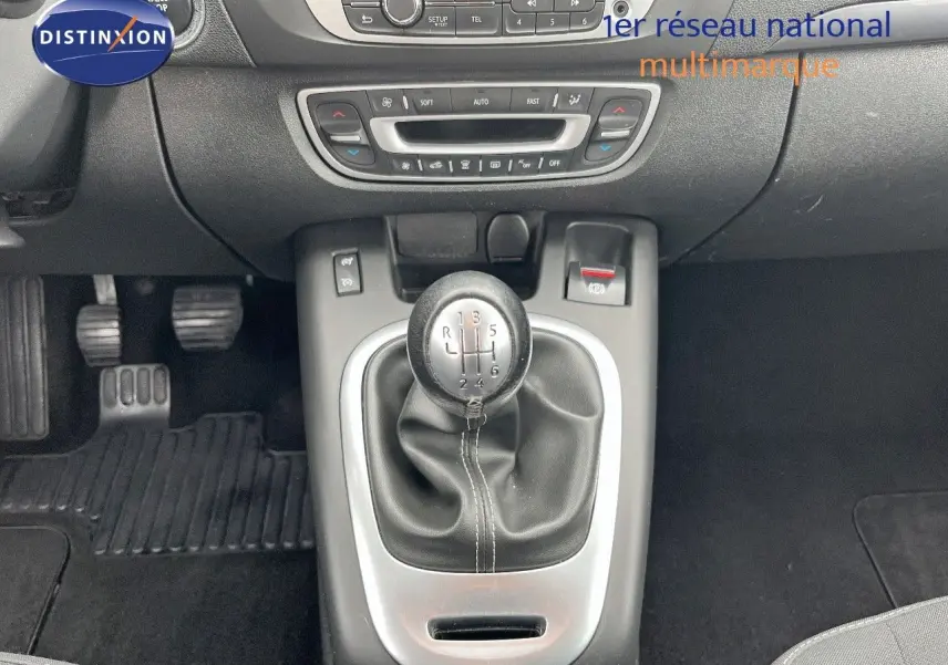 Vue rapprochée du levier de vitesses manuel gris et noir du Renault Scénic III avec commandes de climatisation en arrière-plan.