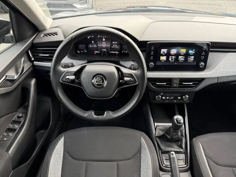 Vue intérieure frontale du Skoda Kamiq 2024 noir Magic nacré, montrant le volant multifonction, tableau de bord digital et levier de vitesses manuel.