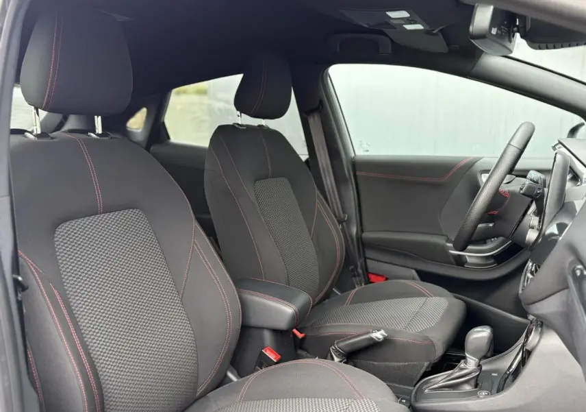 Vue intérieure côté droit du Ford Puma gris Solar 2023, sièges tissu noir avec surpiqûres rouges et volant ST-Line.