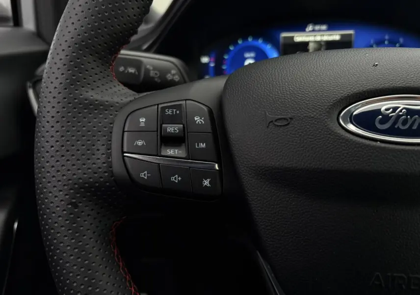 Gros plan sur le volant ST-Line perforé noir avec surpiqûres rouges et commandes multifonctions du Ford Puma 2023.