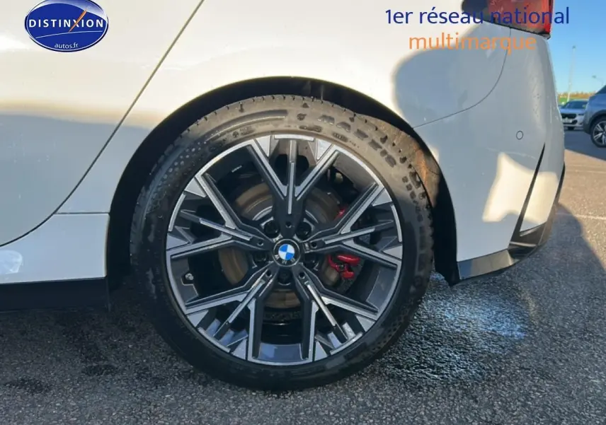 Gros plan sur la roue arrière droite de la BMW Série 1 blanche avec jante 18 pouces bicolore style Y et étrier de frein rouge.