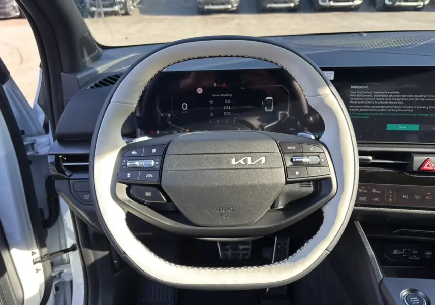 Vue intérieure centrée sur le volant cuir clair du Kia Sportage 2026 blanc nacré avec tableau de bord numérique.