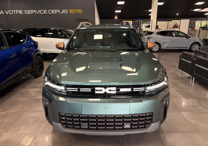 Vue de face du Dacia Bigster Hybrid-G 150 4x4 en Vert Cèdre avec calandre et rétroviseurs cuivrés en showroom.