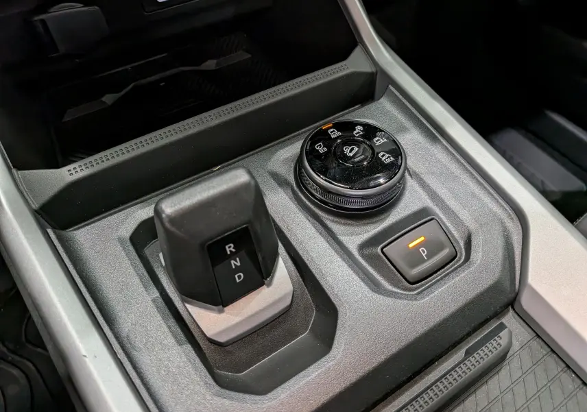 Gros plan sur la console centrale du Dacia Bigster Hybrid-G 150 4x4, montrant la boîte auto et le sélecteur de modes de conduite.