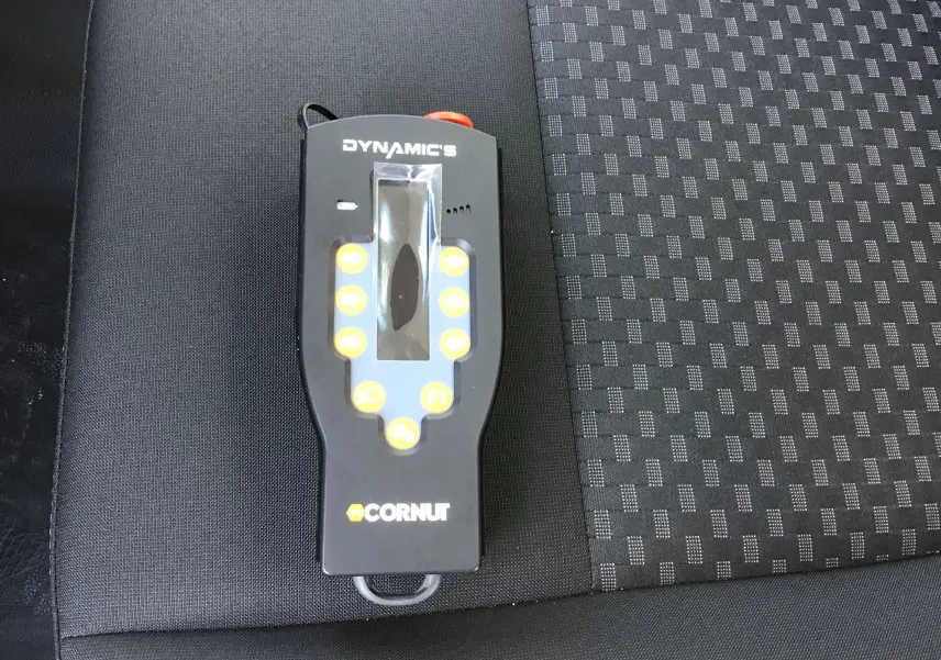 Télécommande noire Dynamics Cornut posée sur un siège tissu gris et noir, intérieur d'un Ford Transit Châssis Cabine blanc.