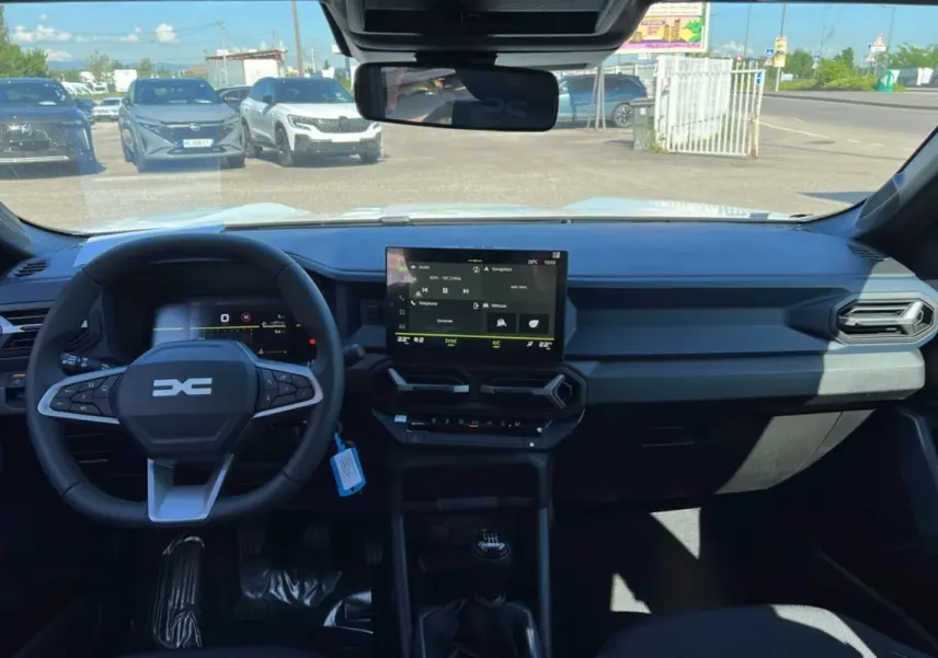 Vue intérieure du tableau de bord du Dacia Bigster blanc glacier 2025, avec écran tactile central et volant multifonction.