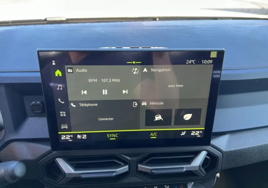 Écran tactile central du tableau de bord du Dacia Bigster 2025, affichant radio, navigation et climatisation.