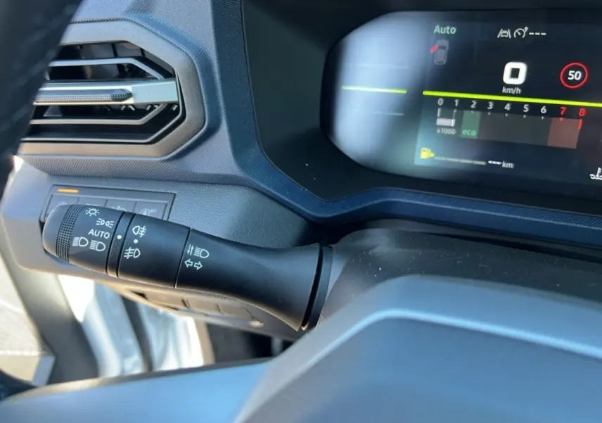 Détail du commodo des phares et tableau de bord numérique du Dacia Bigster blanc glacier 2025, version TCE 130 4X4.