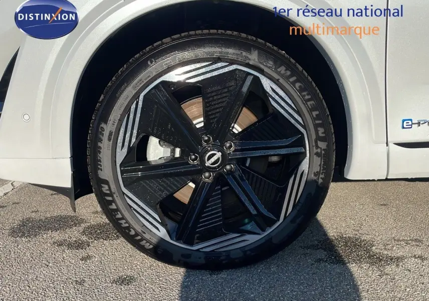 Gros plan sur la roue avant gauche du Nissan Qashqai blanc nacré avec jante noire et détails argentés.