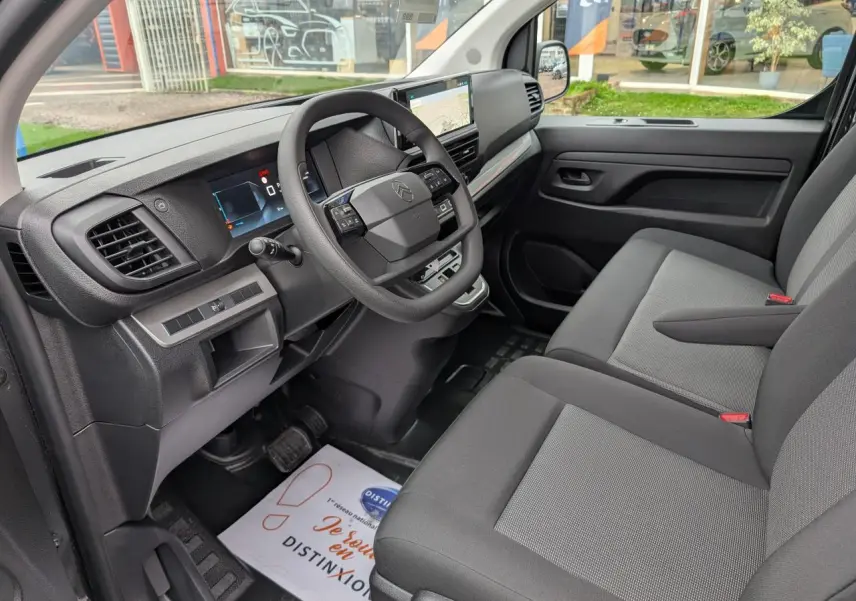 Intérieur côté conducteur du Citroën Jumpy gris 2025 avec tableau de bord moderne et sièges tissu bi-ton noir et gris