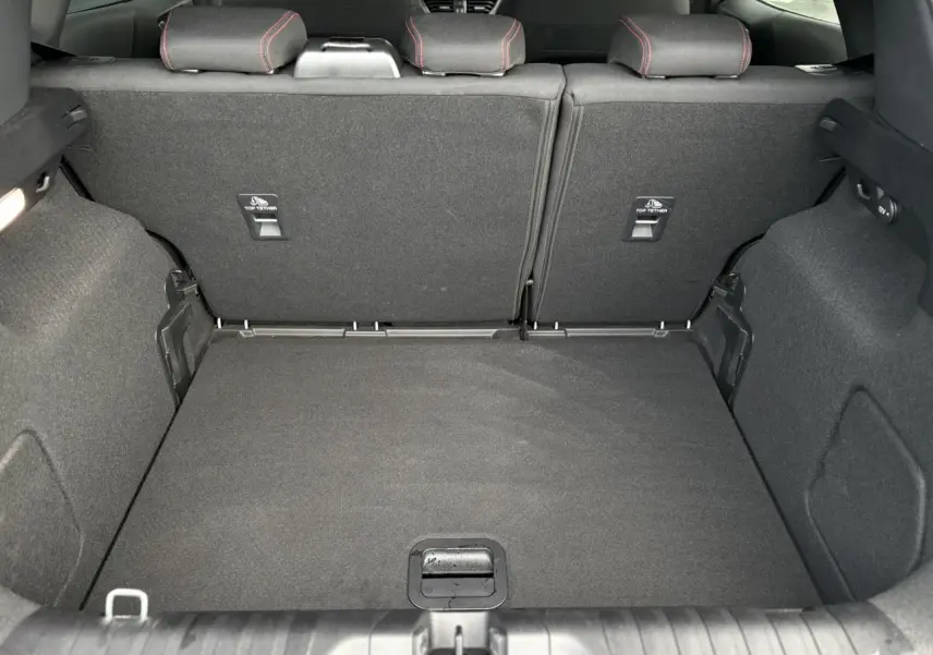 Vue intérieure du coffre spacieux du Ford Puma 2023, avec banquette arrière en tissu gris et surpiqûres rouges visibles.