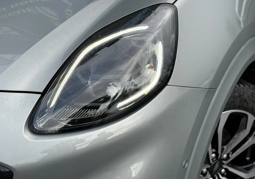 Gros plan sur le phare avant gauche du Ford Puma gris Solar avec jante alliage visible en arrière-plan.