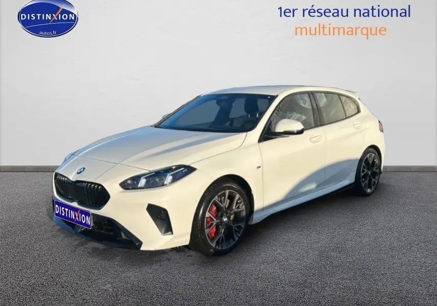 BMW Série 1 blanche alpin vue 3/4 avant droit, avec jantes 18 pouces bicolores et étriers rouges visibles.