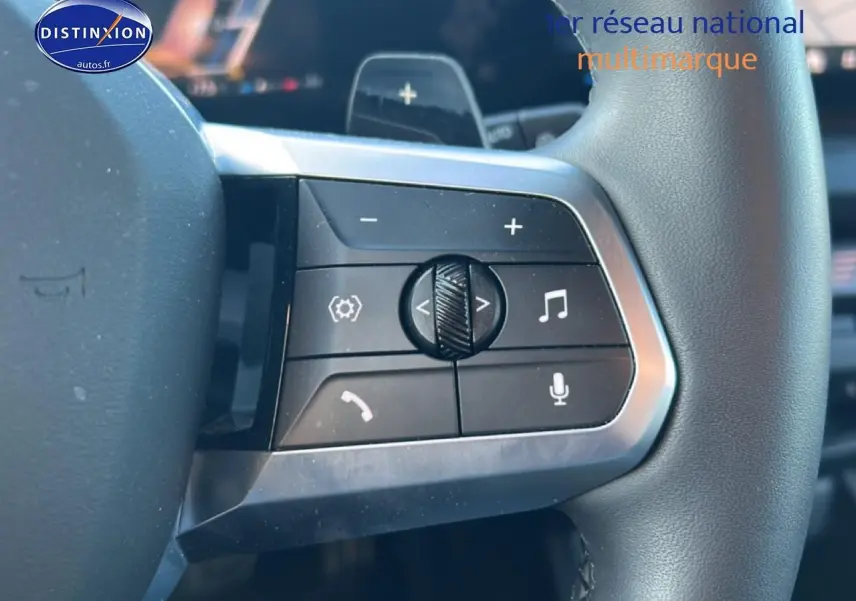 Gros plan sur les commandes gauche du volant de la BMW Série 1 blanche, avec boutons de volume et appels intégrés.