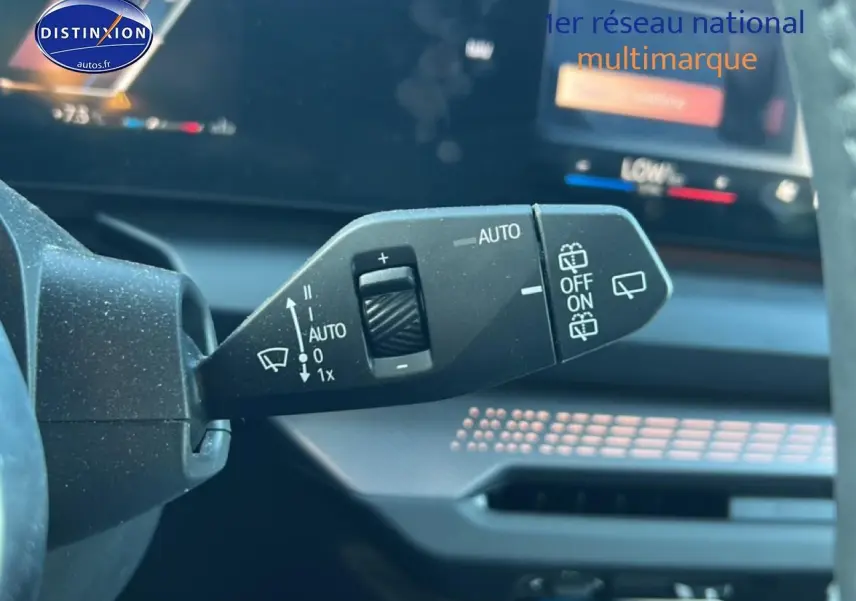 Gros plan sur la manette des essuie-glaces à gauche du volant dans l’habitacle d’une BMW Série 1 blanche.