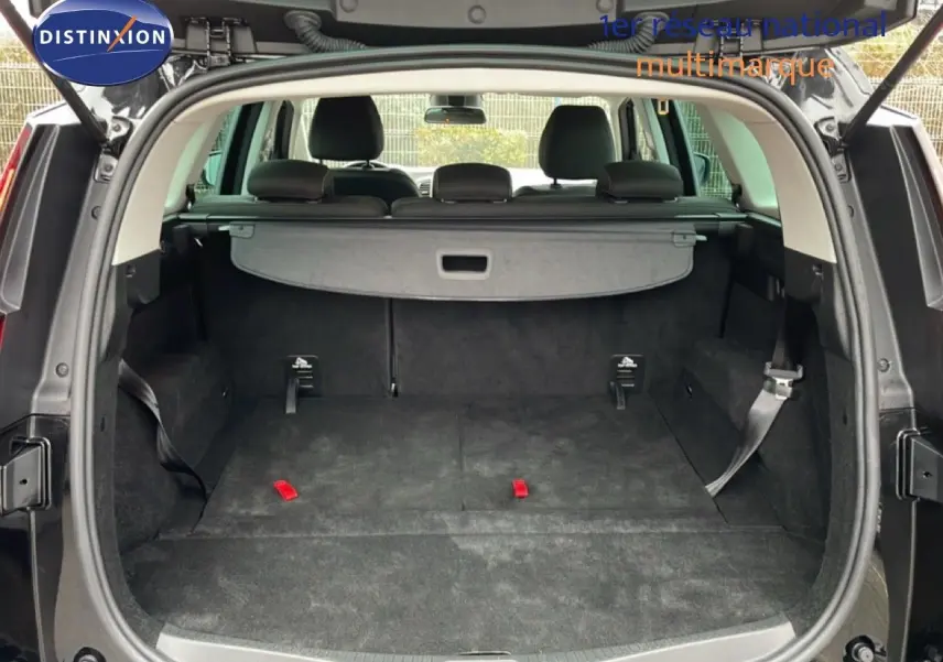 Coffre ouvert en vue arrière d’un Renault Grand Scenic noir étoile métal, avec banquette rabattue et cache-bagages visible.
