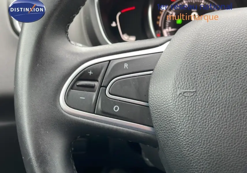 Gros plan sur le volant noir du Renault Grand Scenic 2022, montrant les commandes intégrées à gauche.