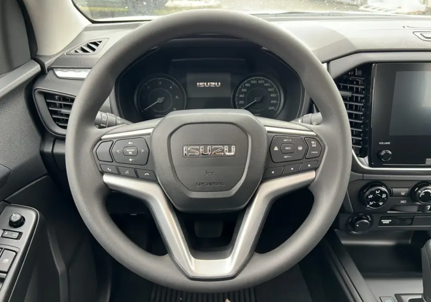 Vue intérieure centrée sur le volant multifonctions gris de l'Isuzu D-MAX 2026 avec tableau de bord et écran tactile.