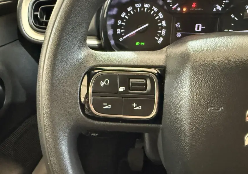 Gros plan sur le volant multifonctions noir de la Citroën C3 2021 avec commandes audio et tableau de bord en arrière-plan.