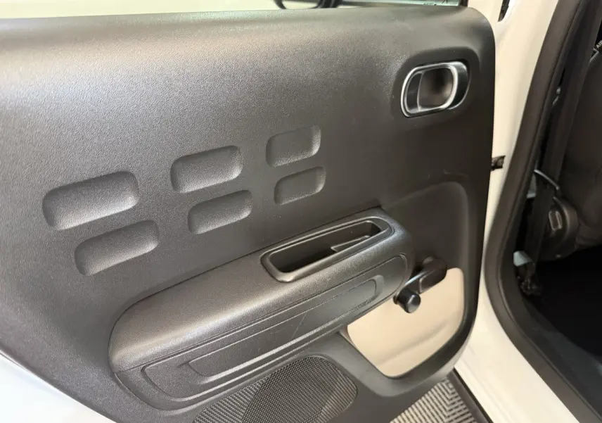 Détail de la porte arrière droite noire avec poignée et manivelle de vitre sur Citroën C3 blanc 2021.