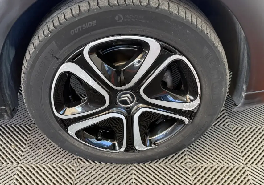 Gros plan sur la jante noire et argentée d'une Citroën C3 blanche, mettant en valeur le logo Citroën central.