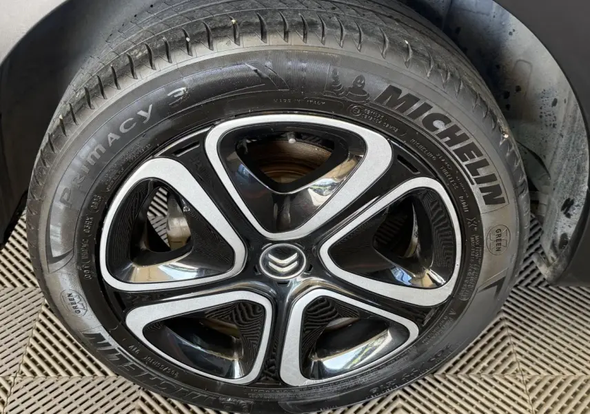 Gros plan sur la roue avant droite d'une Citroën C3 blanche, mettant en valeur la jante noire et argentée avec logo Citroën central.