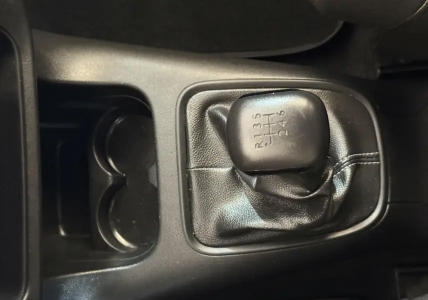 Gros plan sur le levier de vitesses manuel noir de la Citroën C3 BlueHDi 100 S&S BVM6 Feel blanche, intérieur sombre.