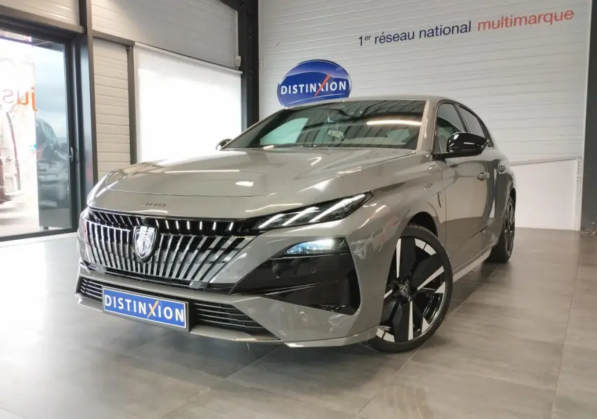 Peugeot 308 hybride gris selenium vue 3/4 avant droit, calandre verticale chromée et jantes alliage noires.
