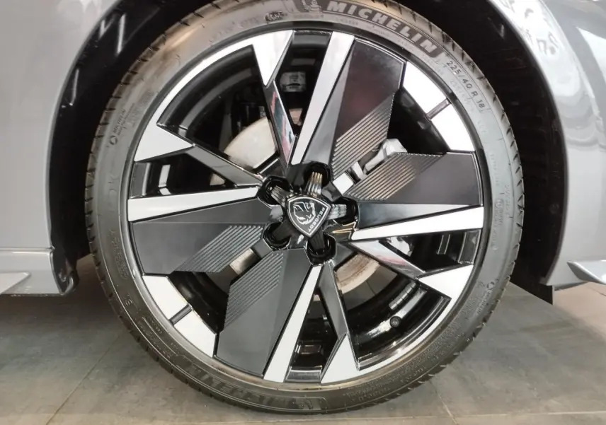 Gros plan sur la jante alliage 18 pouces bi-tons noir et argent avec logo Peugeot, sur roue avant droite gris selenium.