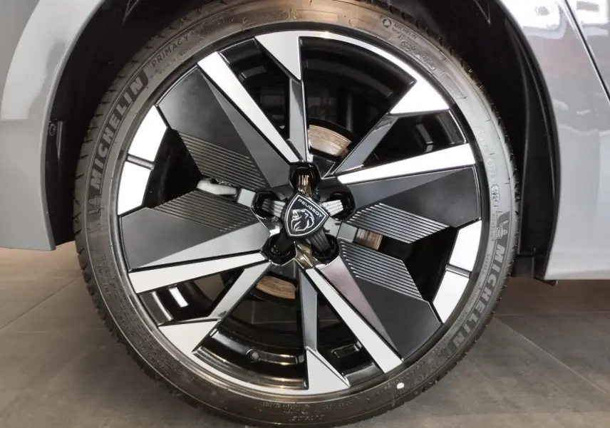 Gros plan sur la jante alliage bi-tons noir et argentée de la Peugeot 308 gris selenium, avec logo central lion.