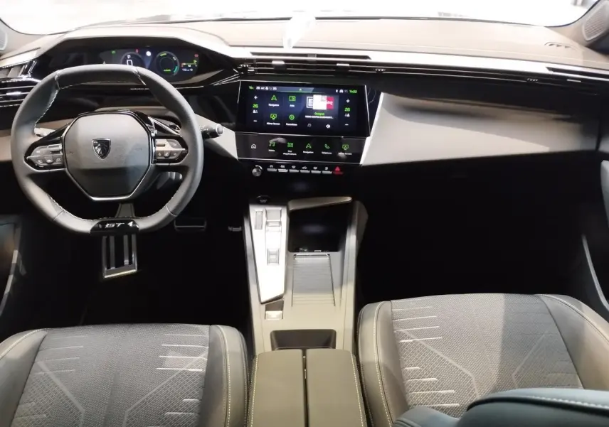 Vue intérieure avant de la Peugeot 308 Hybrid 2026, tableau de bord numérique et volant compact GT cuir noir.