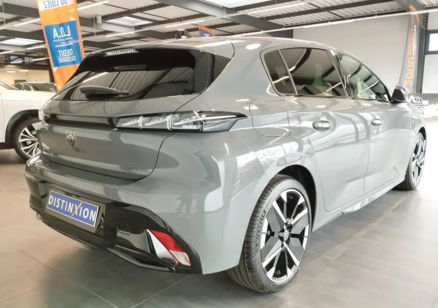 Vue 3/4 arrière droite d'une Peugeot 308 hybride gris selenium avec jantes alliage bi-tons et feux arrière à LED 3 griffes.